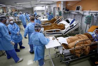 Бригада лікарів і санітарів у захисних костюмах перевозить пацієнта, зараженого коронавірусом, в центр швидкої допомоги лікарні Gemelli в Римі, Італія, 16 березня 2020 року